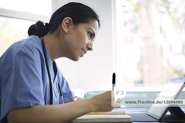 Side view of female doctor using tablet computer while working in medical clinic