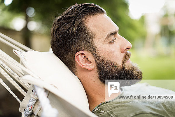Seitenansicht eines Mannes  der sich auf einer Hängematte im Hof entspannt