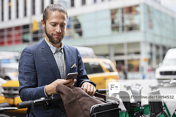 Businessman using mobile phone while standing at parking lot