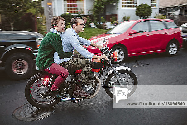 Frau sitzt mit ihrem Freund auf Motorrad auf der Straße