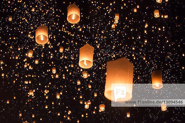 Low angle view of illuminated lanterns against sky at night