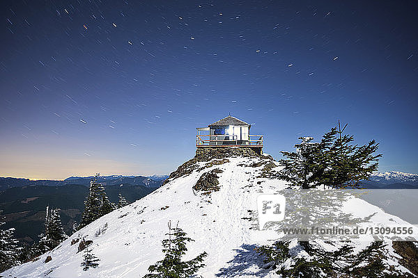 Tiefwinkelansicht der Hütte auf dem schneebedeckten Berg gegen blauen Himmel in der Dämmerung