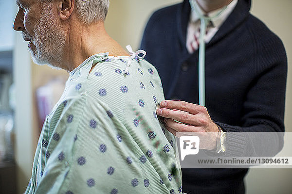 Mittelteil eines männlichen Arztes  der die Atmung des Patienten auf der Krankenhausstation hört