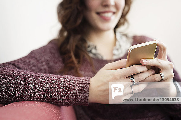 Geschäftsfrau benutzt Smartphone  während sie auf dem Sofa sitzt