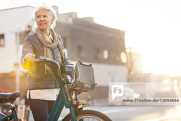 Nachdenkliche ältere Frau steht mit Citi Bike auf der Straße