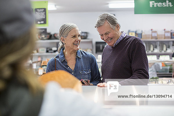 Smiling couple standing by counter at supermarket