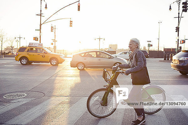 Seitenansicht einer älteren Frau  die mit dem Fahrrad auf der Straße geht