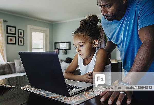 Vater und Tochter benutzen Laptop zu Hause