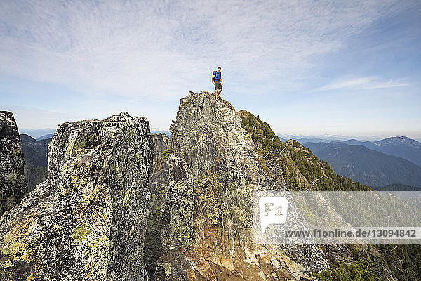 Low angle view of hiker standing on cliff against sky