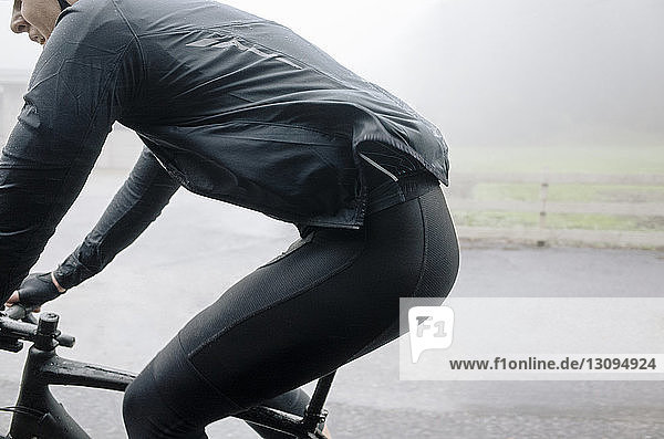 Mann fährt bei nebligem Wetter Fahrrad auf der Straße