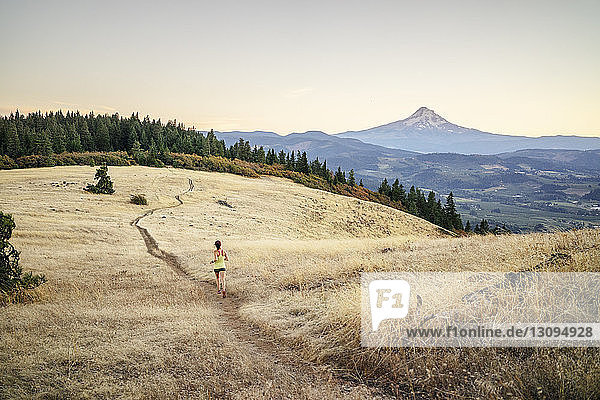 High angle view of woman jogging on mountain against clear sky during sunset