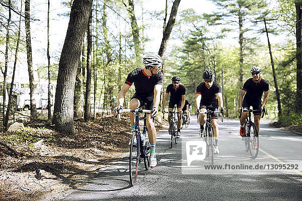Entschlossene männliche Radfahrer  die auf der Landstraße Fahrrad fahren