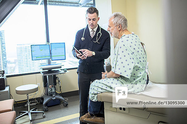 Männlicher Arzt erklärt dem Patienten über Tablet-Computer auf der Krankenstation