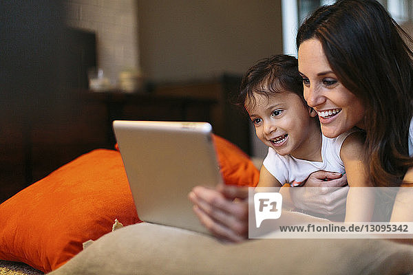 Glückliche Mutter mit Tochter schaut auf Tablet-Computer
