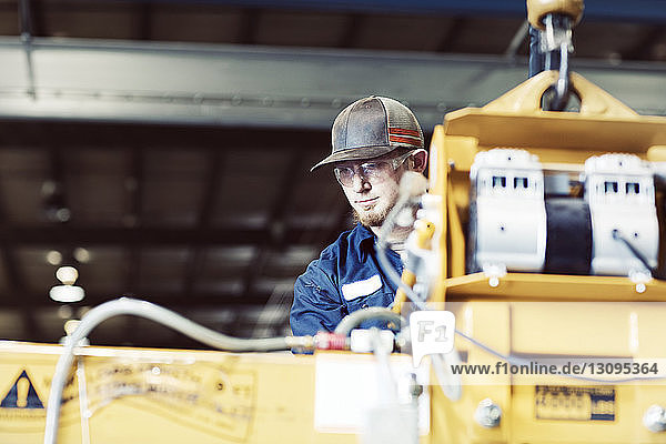 Schwerer junger Arbeiter benutzt Maschine in der Stahlindustrie