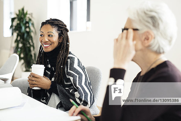 Smiling businesswomen sitting by table during meeting