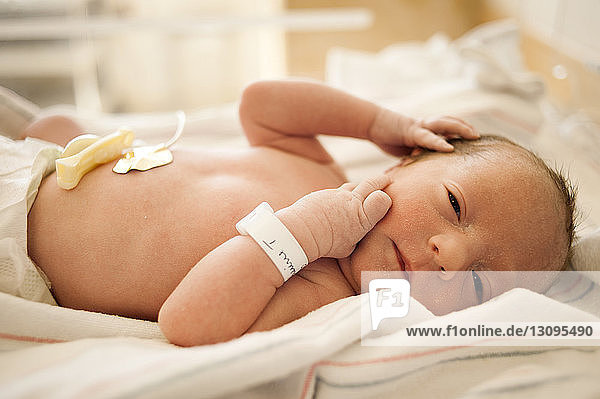 Nahaufnahme eines Neugeborenen  der auf einem Krankenhausbett liegt