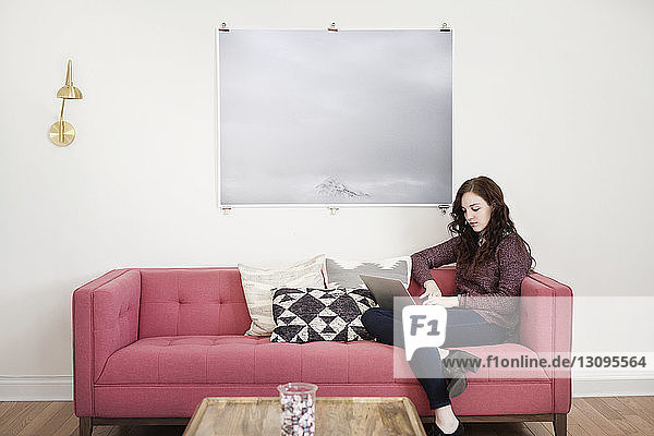 Businesswoman using laptop while sitting on sofa at creative office