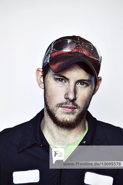 Portrait of young worker wearing cap against white background