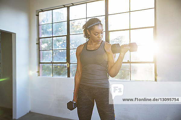 Female athlete lifting dumbbells in gym