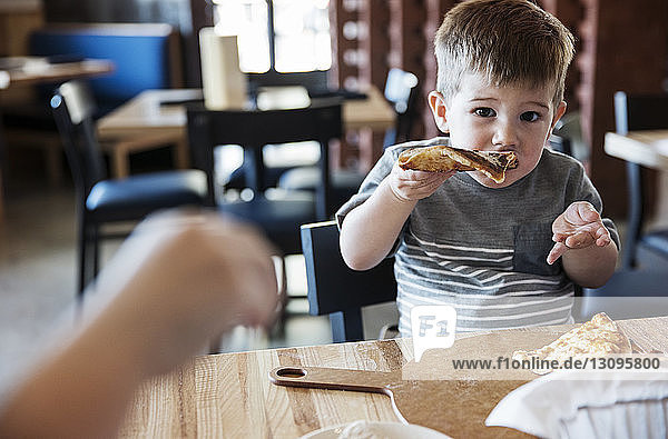 Porträt eines süßen Jungen beim Pizzaessen im Restaurant