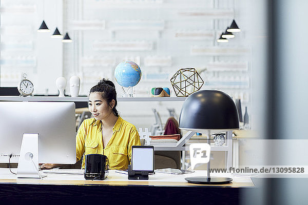Geschäftsfrau  die am Desktop-Computer arbeitet  während sie im Kreativbüro am Schreibtisch sitzt