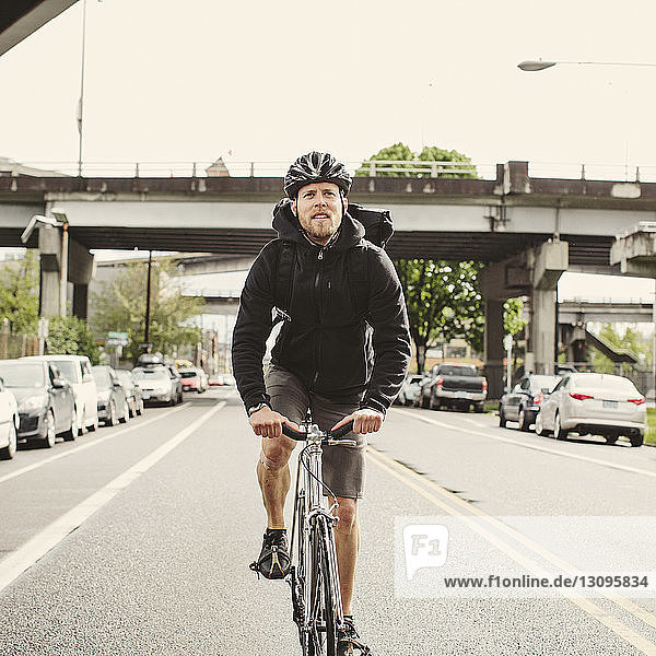 Fahrrad fahrender männlicher Pendler in voller Länge auf Straße gegen Himmel