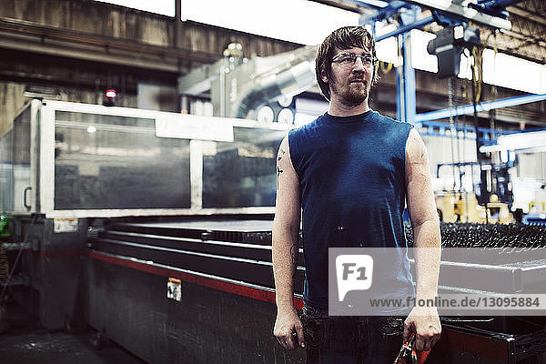 Male worker looking away while standing in industry