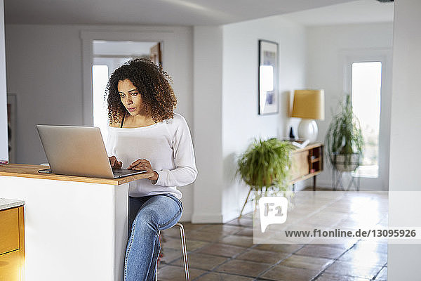 Woman using laptop computer on table at home