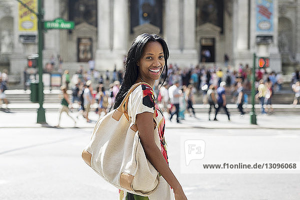Porträt einer glücklichen Frau mit Geldbörse beim Spaziergang auf der Straße