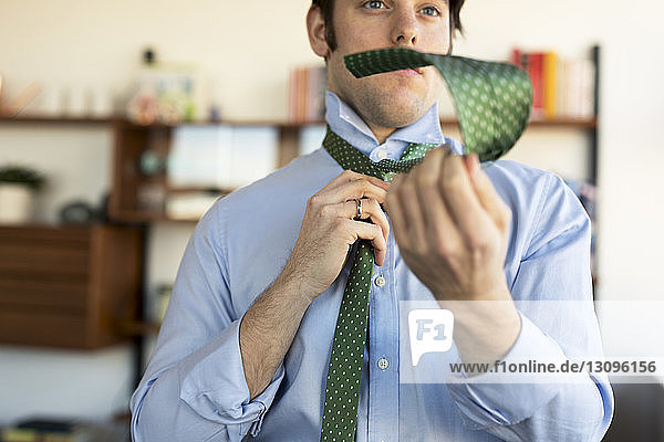 Zuversichtlicher Mann bindet Krawatte zu Hause
