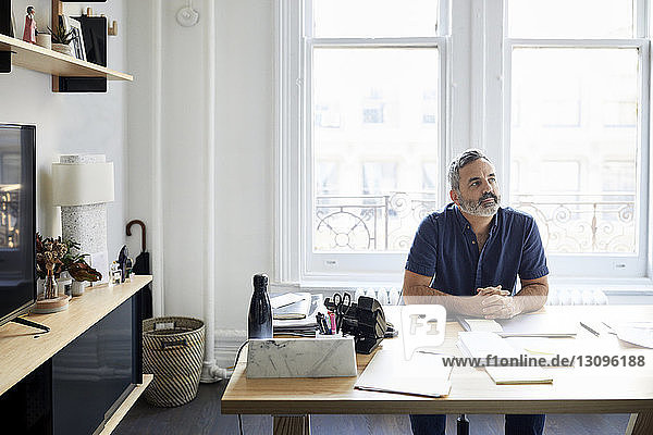 Thoughtful businessman sitting at desk in creative office