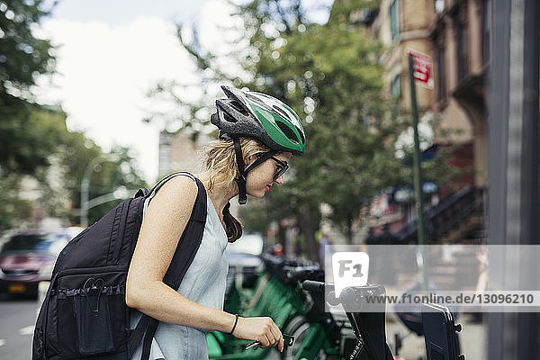 Seitenansicht einer Frau  die ein auf der Straße geparktes Fahrrad betrachtet