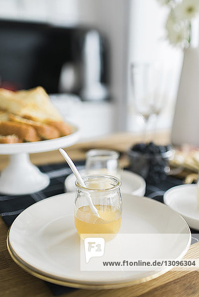 Hochwinkelansicht von Honig in einem Glas mit Tellern auf dem Tisch