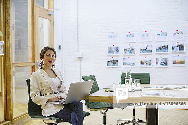 Porträt einer lächelnden Geschäftsfrau mit Laptop-Computer im Sitzungssaal