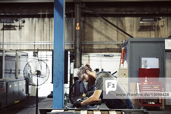 Seitenansicht eines Arbeiters mit Hammer und Meißel in einer Stahlfabrik