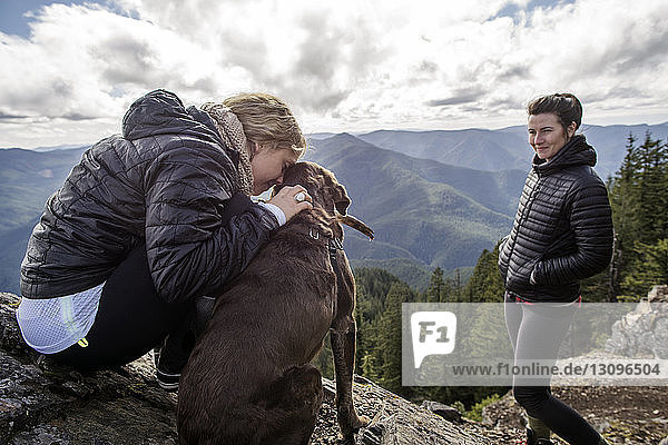 Frauen genießen mit Hund am Bergfelsen beim Wandern