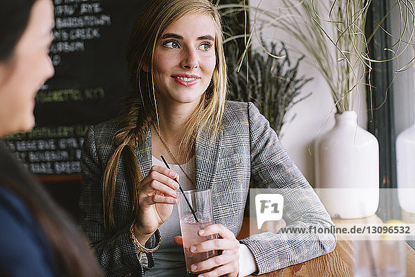Woman looking at smiling friend while sitting in restaurant
