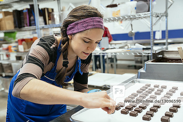 Köchin arrangiert Schokoladenstücke in der Fabrik in einem Tablett