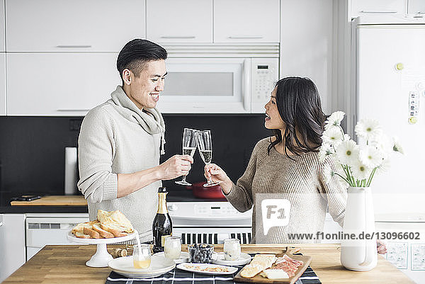 Glückliches Paar trinkt zu Hause in der Küche auf Prosecco