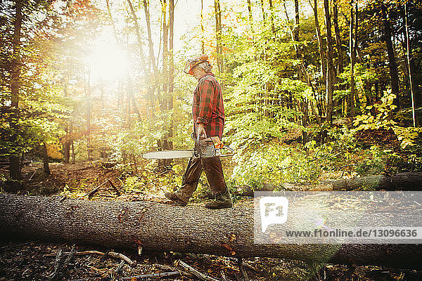 Side view of lumberjack walking on log in forest
