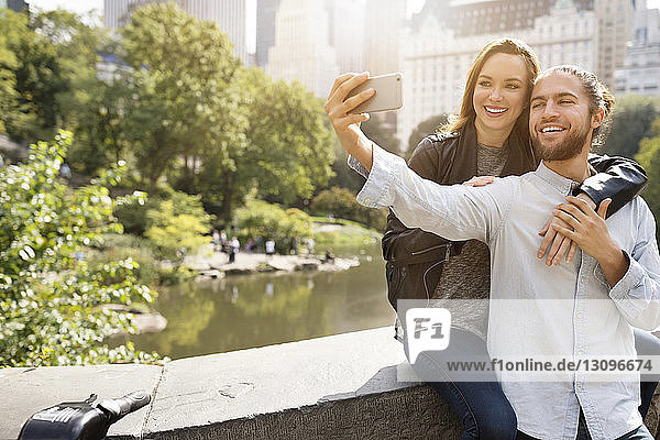 Happy couple taking selfie while leaning on retaining wall