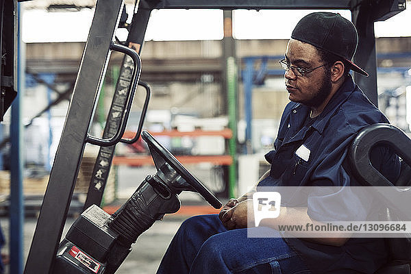 Worker sitting in forklift at industry