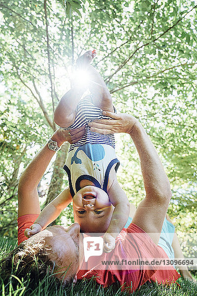 Vater hält Baby auf dem Kopf  während er im Hinterhof liegt