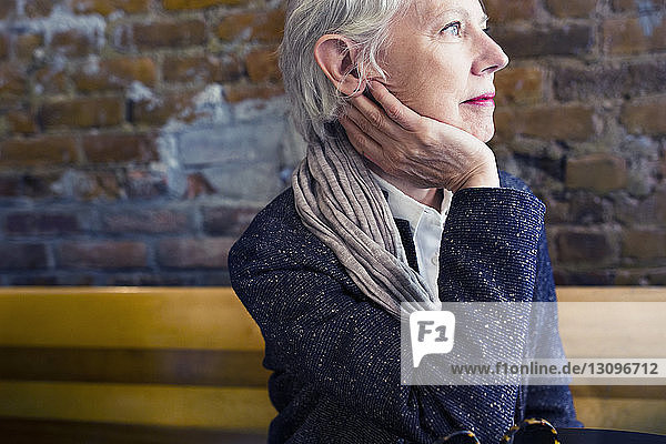 Nachdenkliche ältere Frau sitzt im Bürgersteig-Café