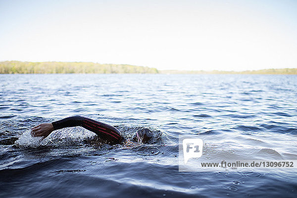 Cropped image of woman swimming in lake against clear sky