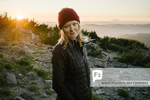Porträt einer Frau  die bei Sonnenuntergang auf einem Berg gegen den Himmel steht