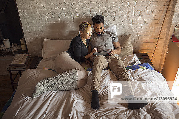 Draufsicht eines multiethnischen Paares mit Tablet-Computer am Bett