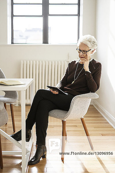 Senior businesswoman using digital tablet while sitting in office