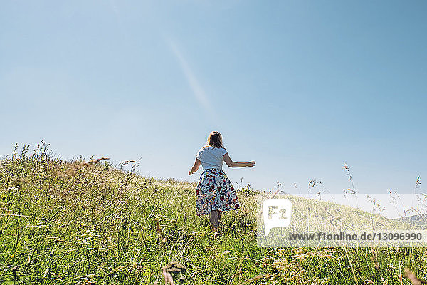 Rückansicht einer Frau auf einem Grasfeld gegen den Himmel im Sommer